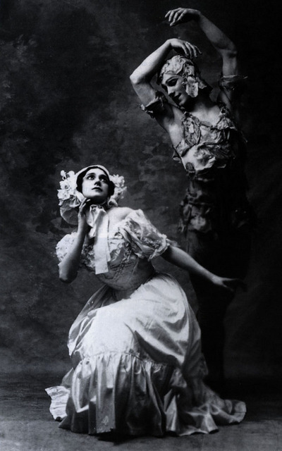 Black and white image of a ballerina in a white dress looking up at a male dancer dressed as a rose
